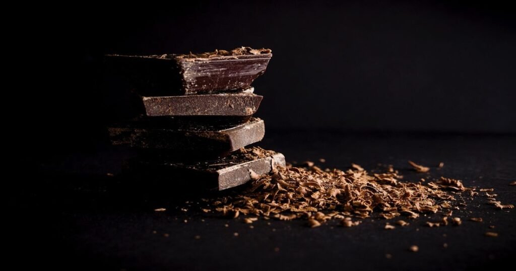 A bar of dark chocolate with cocoa beans scattered around.